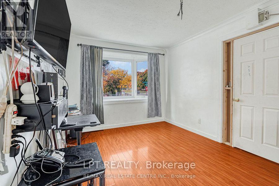 A room with a wooden floor and a window with a view of trees.