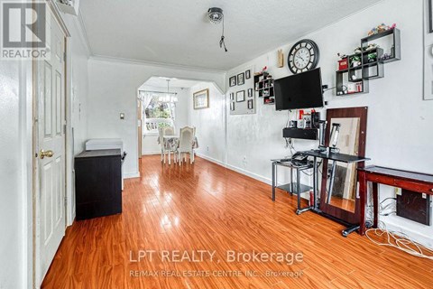 A living room with wood floors and a television on the wall.