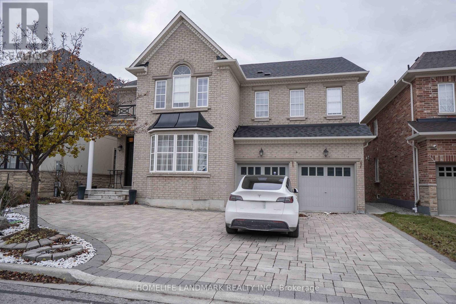A white car is parked in front of a brick house.