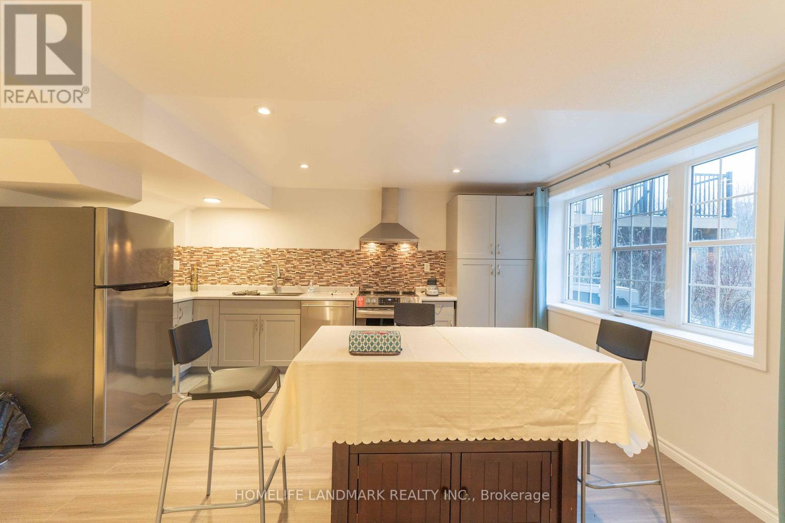 A kitchen with a table and chairs in the foreground and a refrigerator in the background.