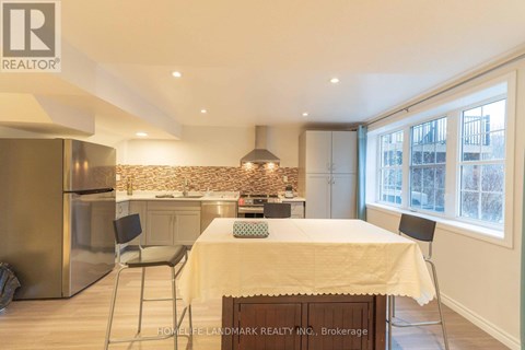 A kitchen with a table and chairs in the foreground and a refrigerator in the background.