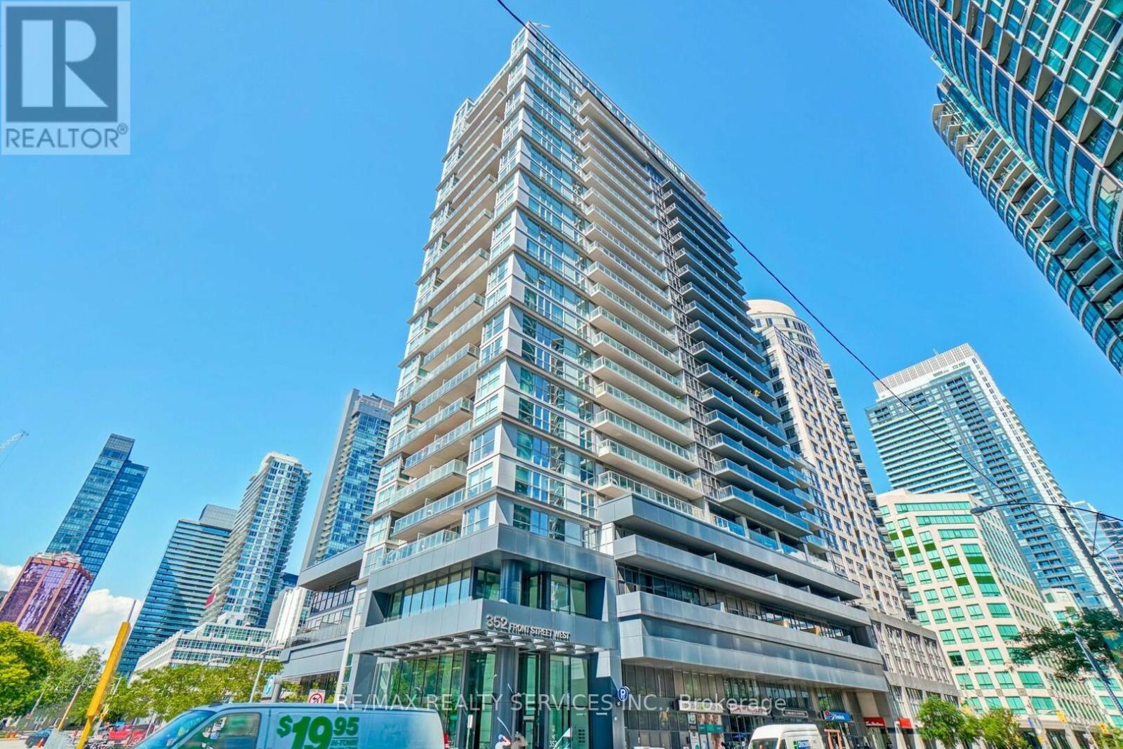A tall building with a glass facade stands in front of other skyscrapers.