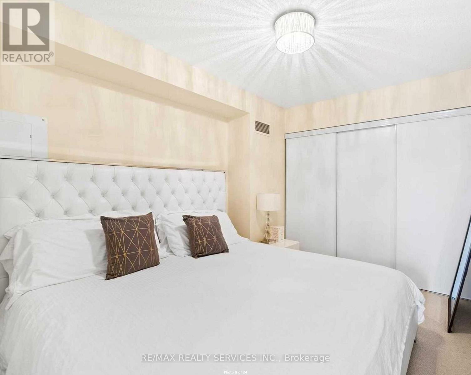 A bedroom with a white bed and a white ceiling.