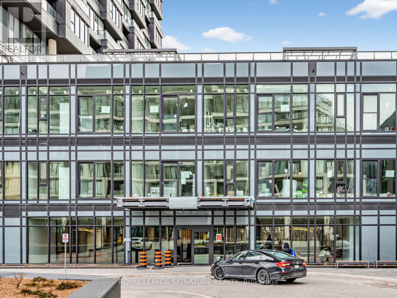 A modern building with a glass facade and a car parked in front.