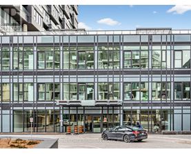 A modern building with a glass facade and a car parked in front.