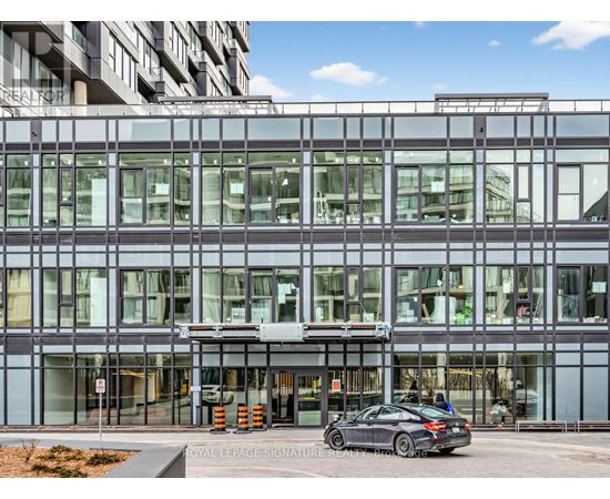 A modern building with a glass facade and a car parked in front.