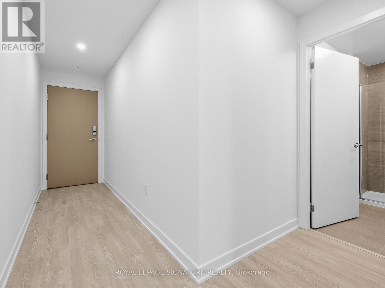 A white hallway with a brown door and a white door on the other side.