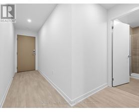 A white hallway with a brown door and a white door on the other side.