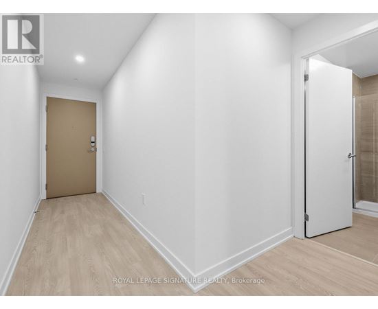 A white hallway with a brown door and a white door on the other side.