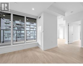 A spacious room with a large window overlooking a building and a doorway leading to another room.