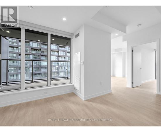 A spacious room with a large window overlooking a building and a doorway leading to another room.