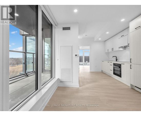 A spacious kitchen with white cabinets and a large window.