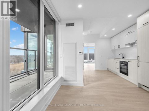 A spacious kitchen with white cabinets and a large window.