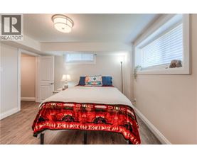 A bedroom with a bed covered in a red and black patterned blanket.