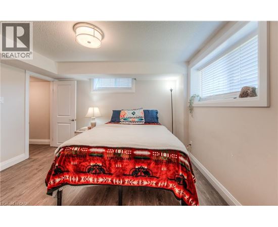 A bedroom with a bed covered in a red and black patterned blanket.