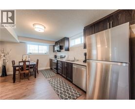 A modern kitchen with a wooden table and stainless steel appliances.