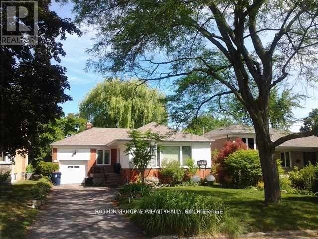A house with a driveway and a tree in front of it.
