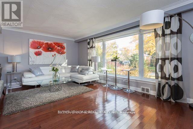 A living room with a white sofa set and a painting of red flowers on the wall.