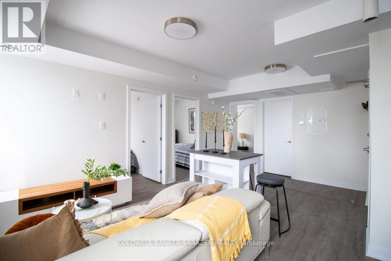 A well-lit, modern bedroom with a bed, couch, and a small table with a plant on it.