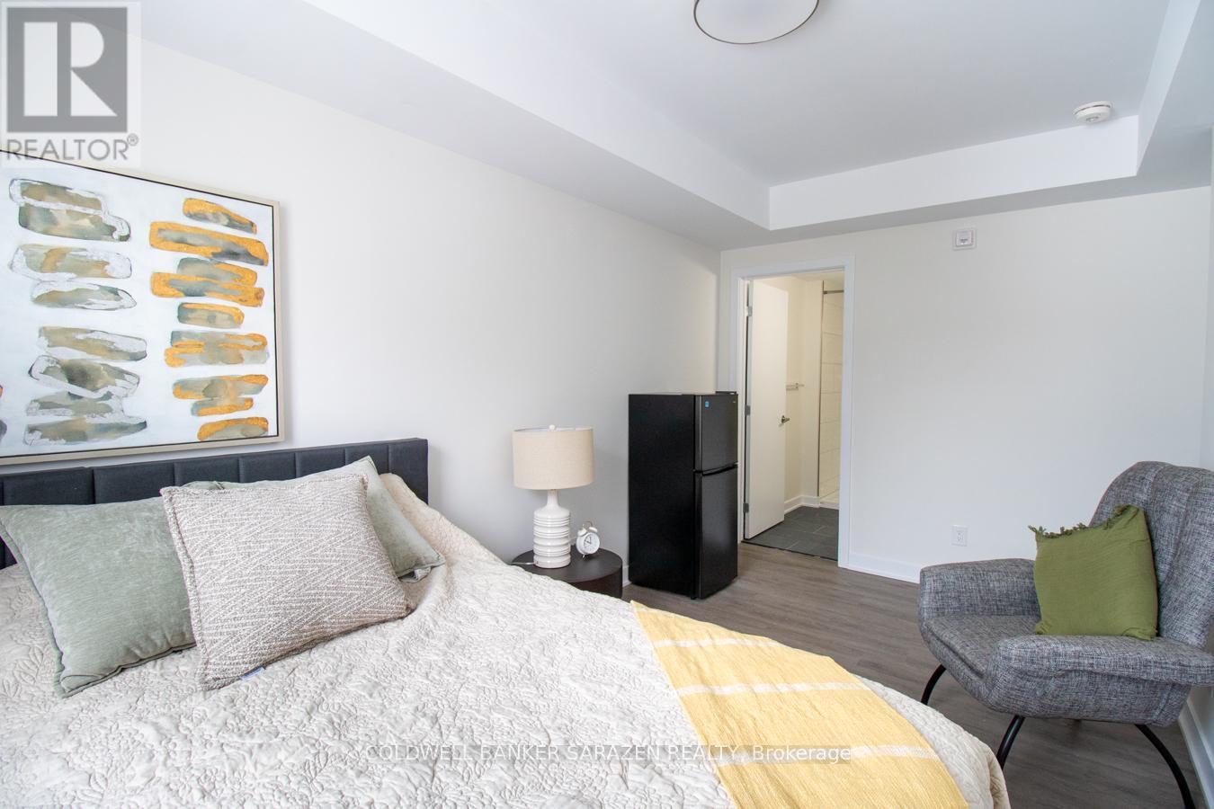 A bedroom with a bed, chair, and a painting on the wall.