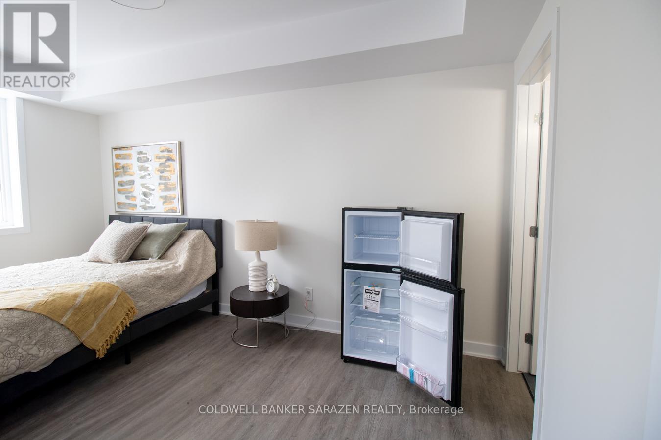 A bedroom with a bed, nightstand, and a small refrigerator.