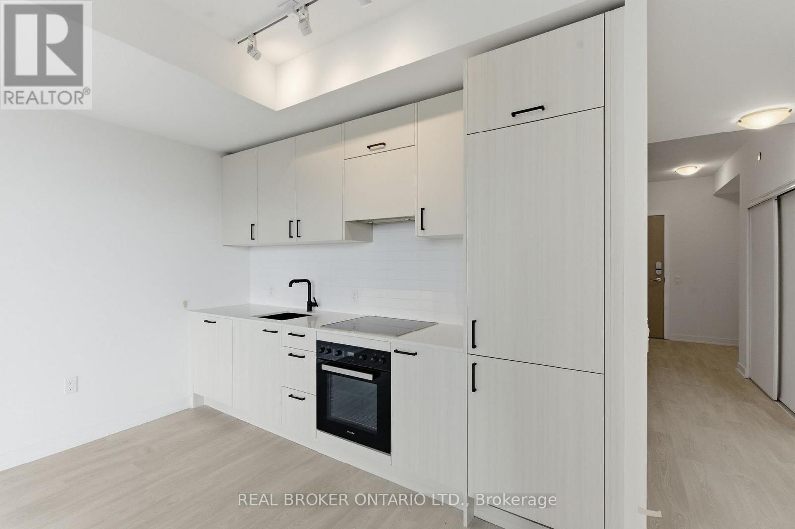 A white kitchen with a black oven and wooden floors.