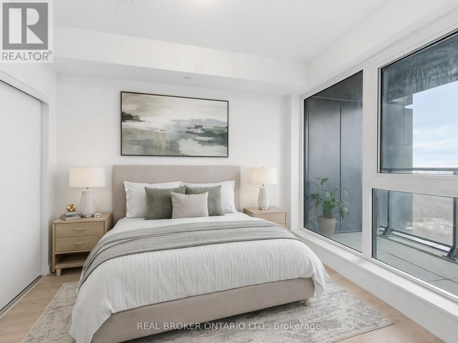 A bedroom with a large bed, a nightstand with a lamp, and a painting on the wall.