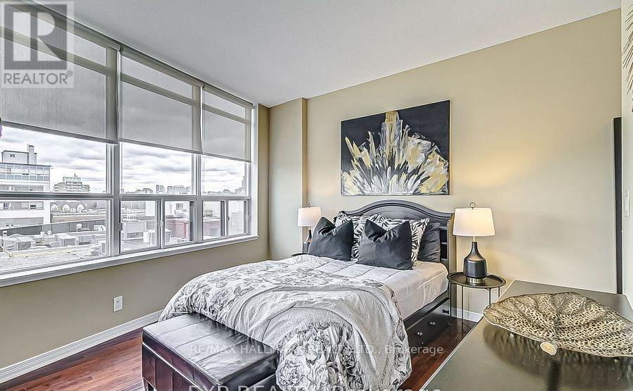 A bedroom with a large bed and a large window overlooking a cityscape.