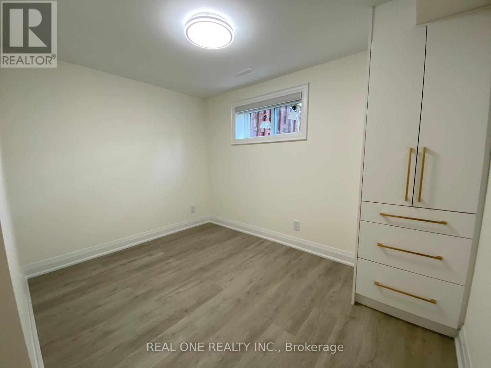A bedroom with a window and a wooden floor.