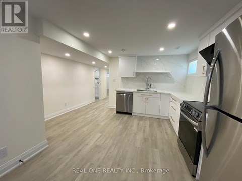 A kitchen with a stainless steel refrigerator and wooden flooring.