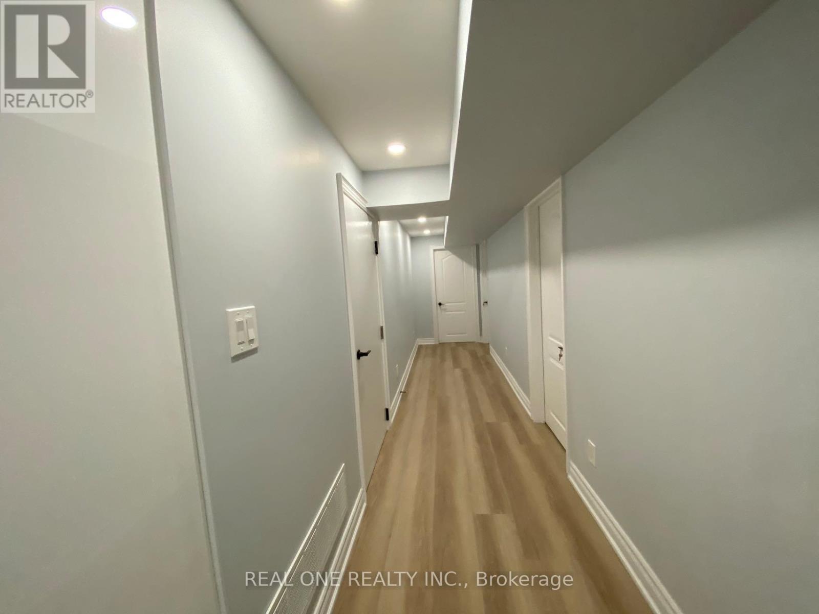 A long hallway with white walls and wood flooring.