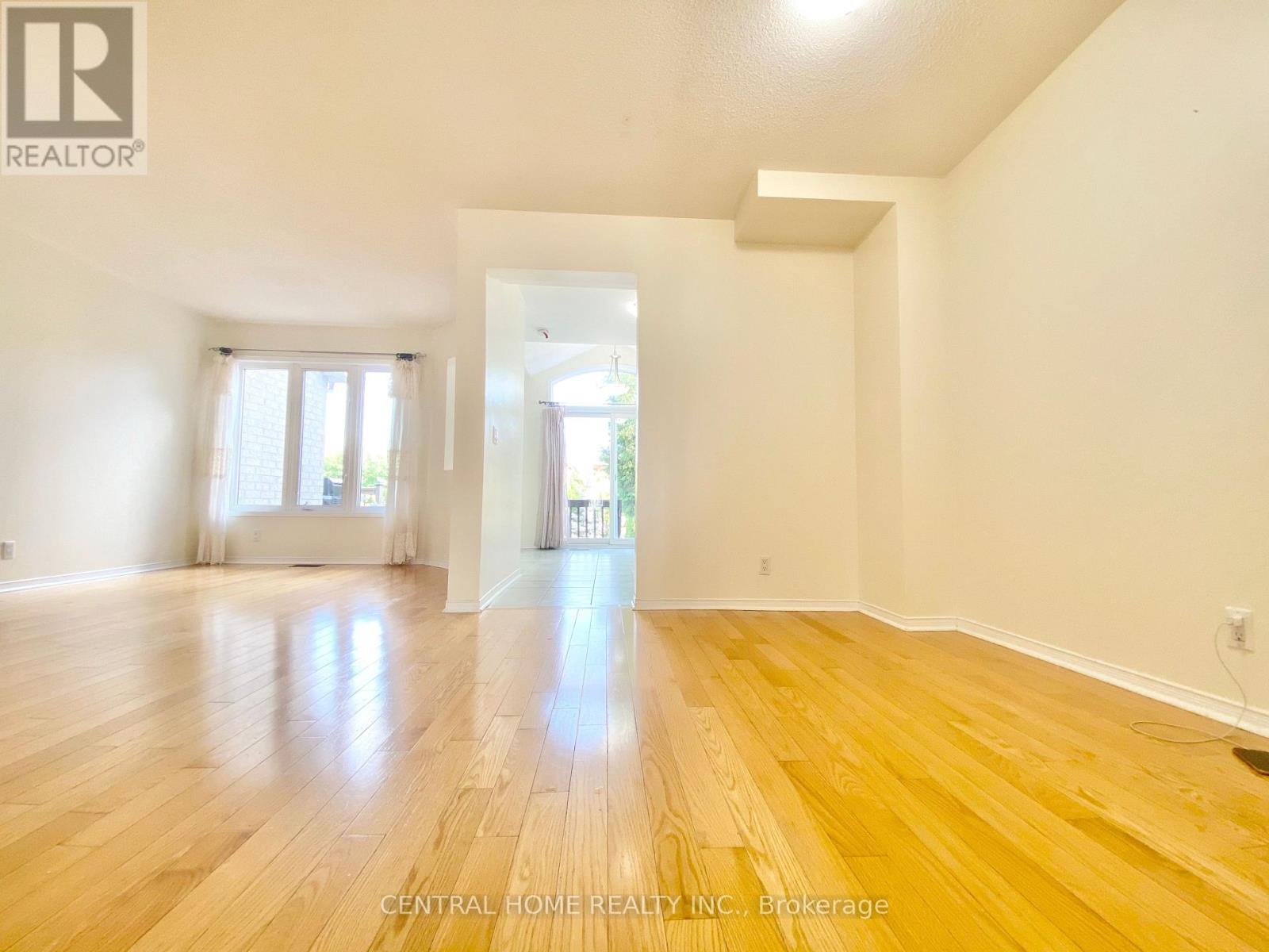 A spacious room with wooden flooring and white walls.