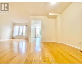A spacious room with wooden flooring and white walls.