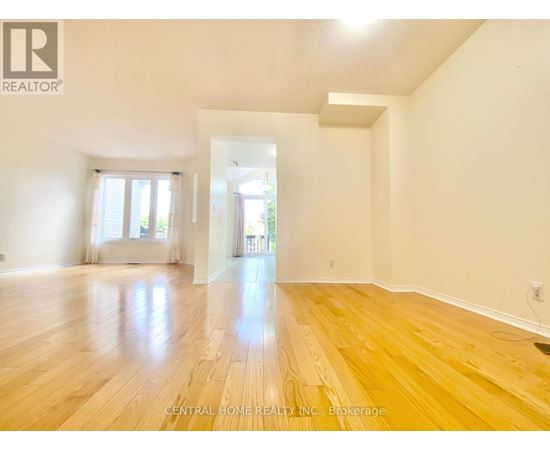 A spacious room with wooden flooring and white walls.
