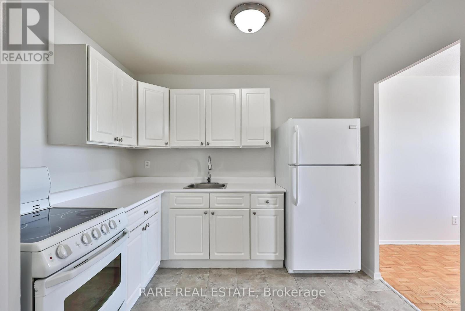 A white kitchen with a refrigerator, oven, and cabinets.