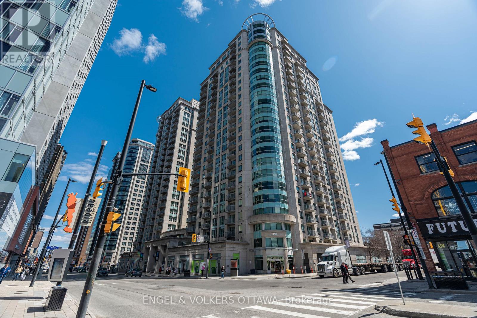 A tall building with many windows is in the middle of a city street.