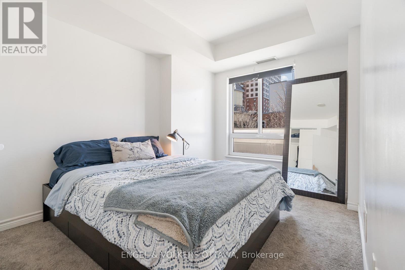A bedroom with a large bed and a view of a city street through the window.