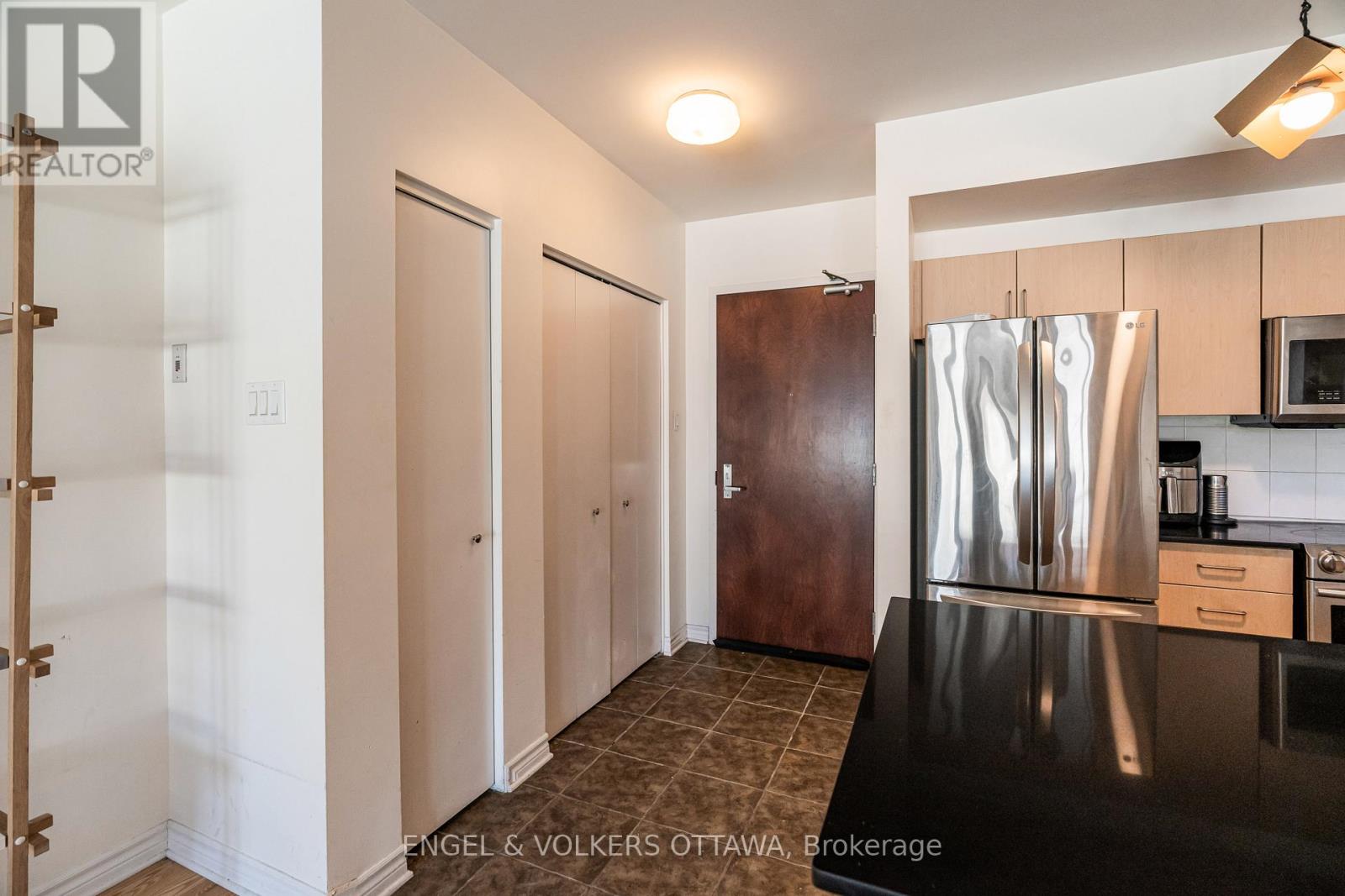 A kitchen area with a stainless steel refrigerator and a black countertop.