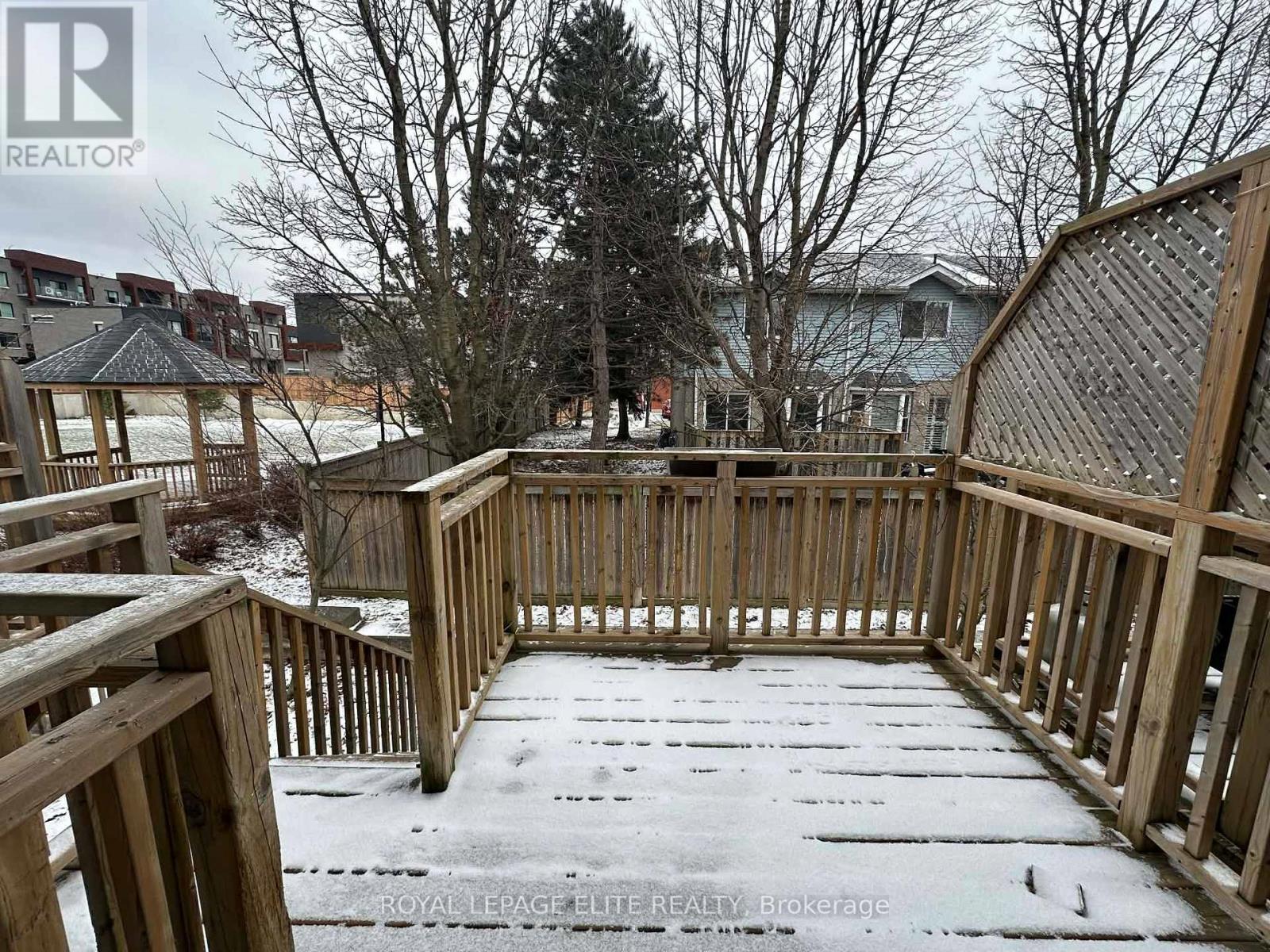 A wooden deck with snow on it and a house in the background.