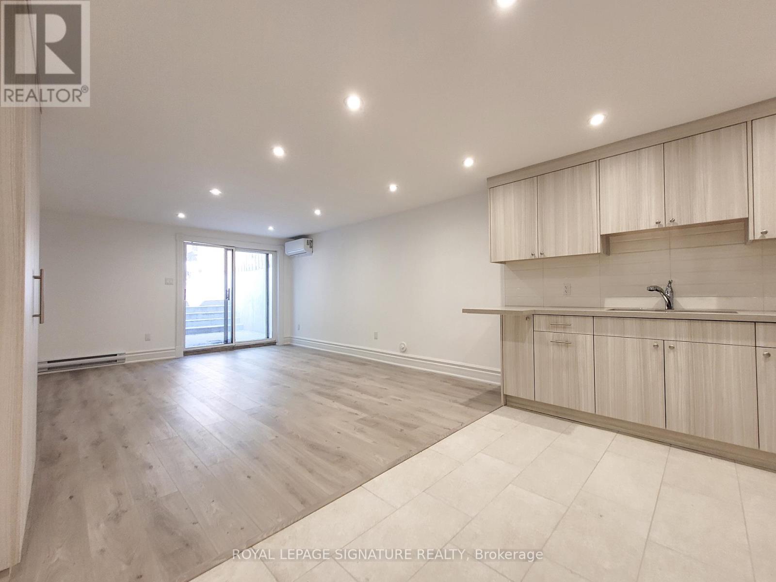 A spacious room with wooden flooring and white walls.