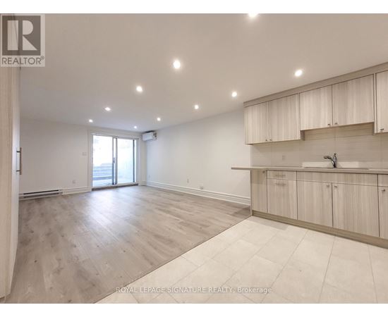 A spacious room with wooden flooring and white walls.