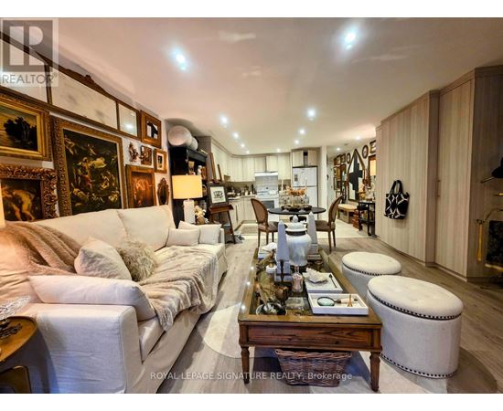 A well-lit, spacious living room with a white sofa, wooden coffee table, and a variety of decorative items.