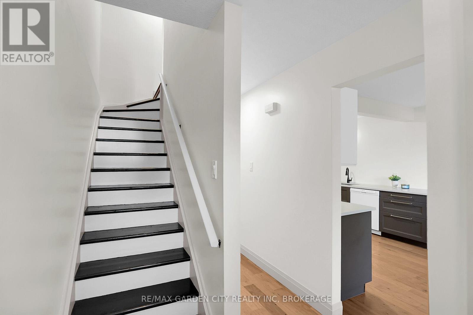 A staircase with black and white stripes on the steps and a kitchen area with a counter and cabinets.
