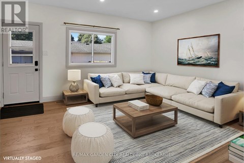 A living room with a white couch and a painting on the wall.