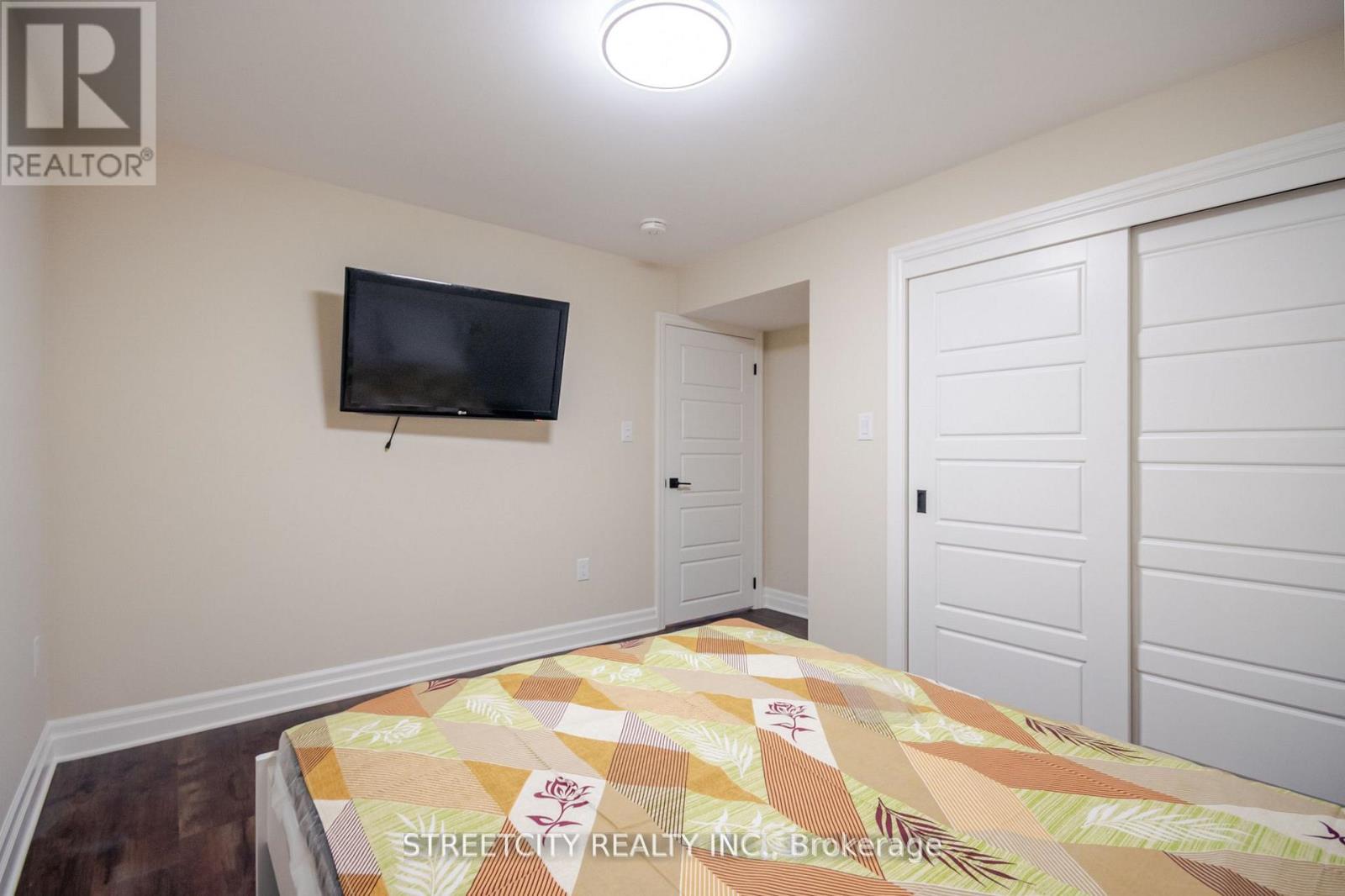 A bedroom with a bed, a flat screen TV and a window.
