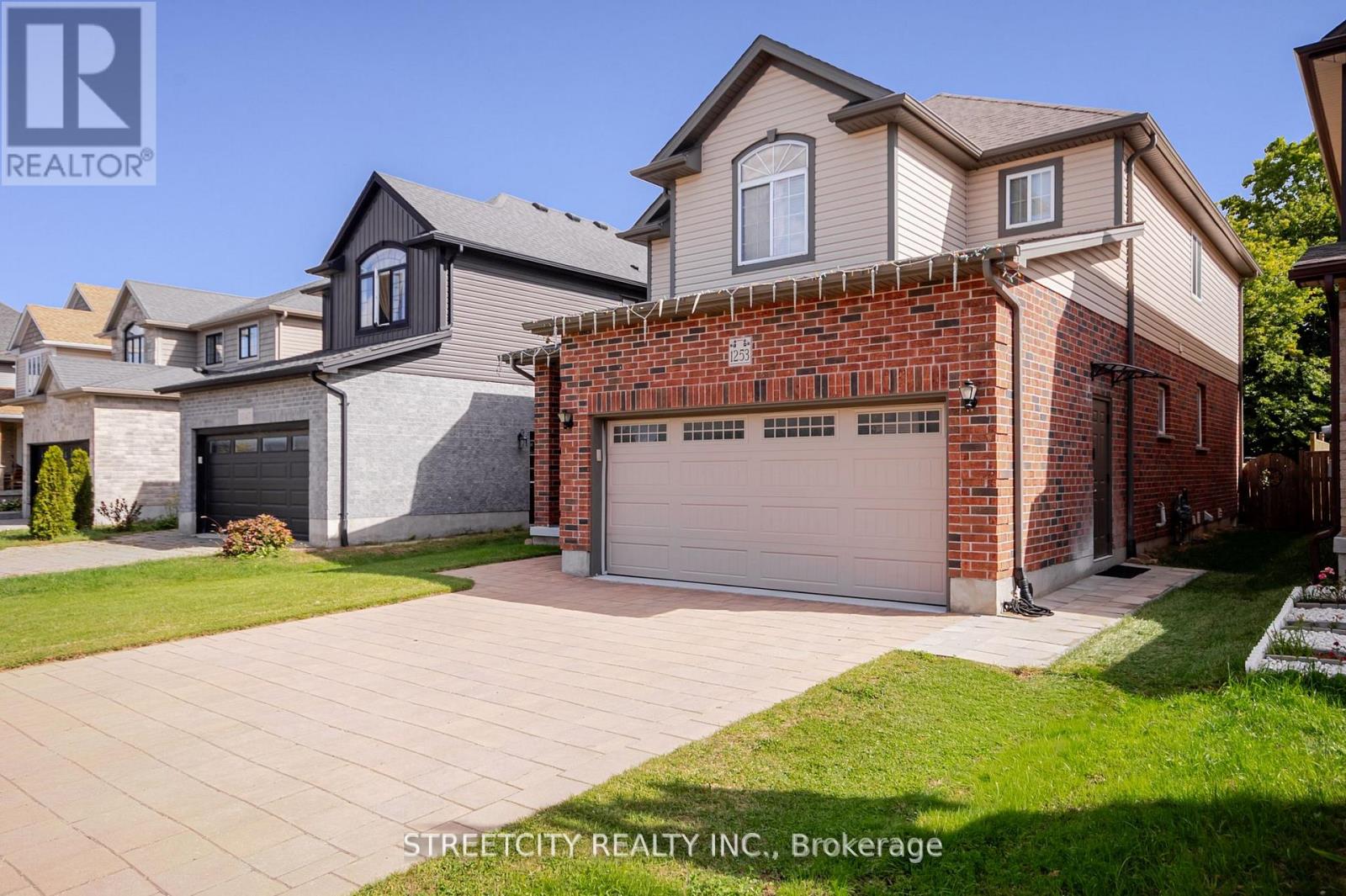 A house with a brick wall and a garage door is for sale.