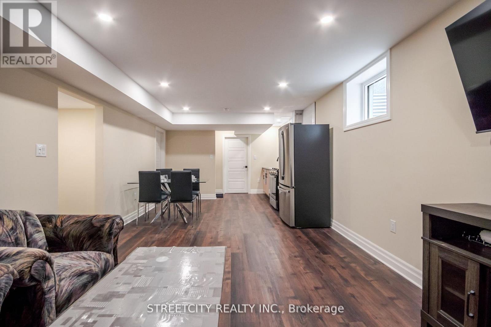 A living room with a couch, chairs, and a television.