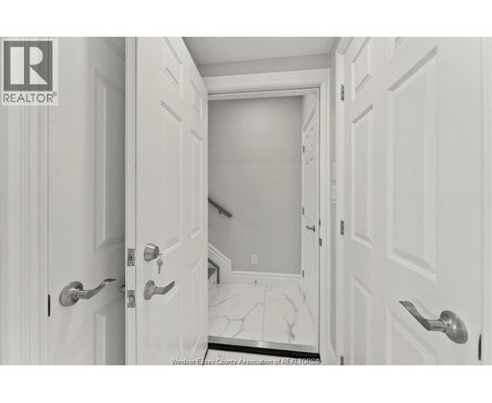 A hallway with white doors and a marble floor.
