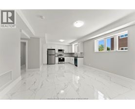 A spacious kitchen with white marble flooring and modern appliances.