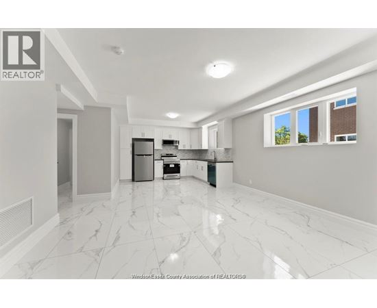 A spacious kitchen with white marble flooring and modern appliances.